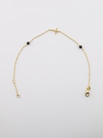 Zlatý náramok s krížikom a čiernymi guľôčkami